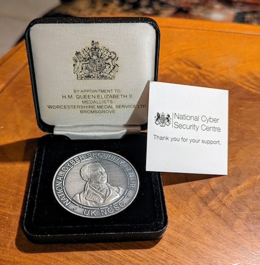 National Cyber Security Center (NCSC) challenge coin gracely provided by the UK government following our research